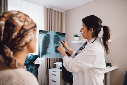 Una doctora examina una radiografía en su consulta, junto a una paciente.