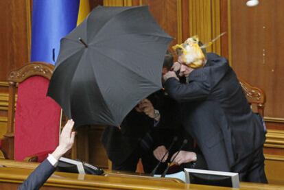 Escoltas protegen con un paraguas al presidente de la Cámara, Volodomir Litvin, de los huevos arrojados por los diputados de la oposición.