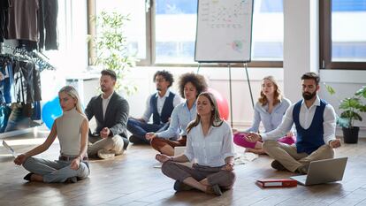 Grupo de empleados en una sesión de meditación en el trabajo.