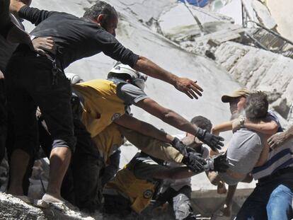 Voluntarios de rescate del casco blanco y civiles recuperan a un niño de entre los escombros de un edificio destruido durante un ataque aéreo de las fuerzas del régimen sirio en la ciudad de Ariha, en la provincia Idlib (Siria).
