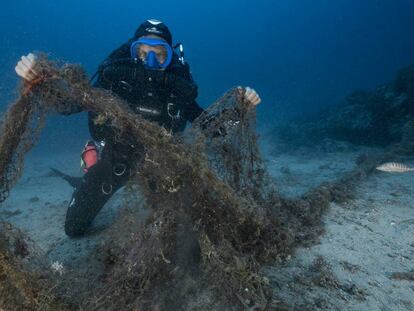 Un buzo que explora los fondos marinos muestra una red de pesca abandonada que acaba de encontrar en Marsella (Francia) en agosto de 2017.