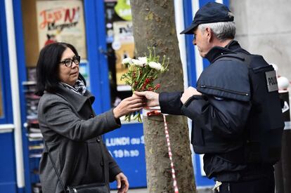 Una mujer entrega un ramo de flores a un policía para que lo coloque en la zona del atentando en la Rue de Charonne.