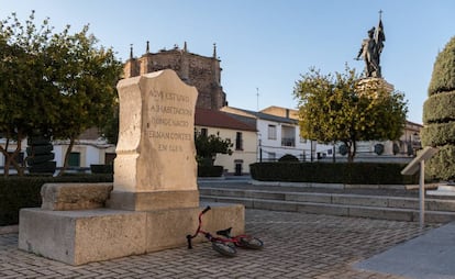 Monolito que indica la ubicación de la casa natal de Hernán Cortés y al fondo su estatua, en Medellín (Badajoz).