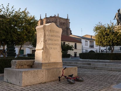 Monolito que indica la ubicación de la casa natal de Hernán Cortés y al fondo su estatua, en Medellín (Badajoz).