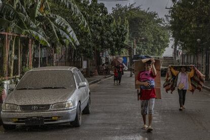 Varios residentes de Talisay caminan por una calle cubierta de cenizas del volcán Taal.