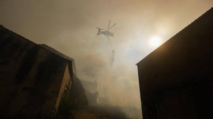 Un helicóptero arroja agua sobre un incendio forestal en la Villa Pisao, en Mealhada (Portugal). Mas de 319 bomberos, 94 vehículos terrestres y seis helicópteros y aviones luchan por sofocar el incendio forestal.