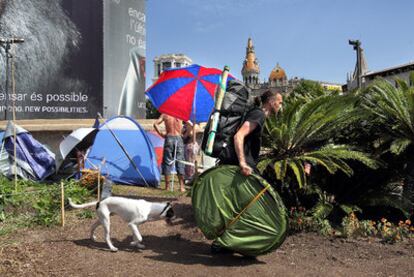 Uno de los acampados de la plaza de Catalunya carga con sus enseres.