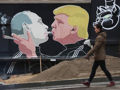 Uma mulher ao lado de um mural com a imagem de Trump e Putin em Vilnius, na Lituânia.