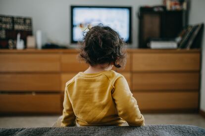 Una niña ve la televisión tradicional en casa.