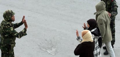 Unas personas pasan con las manos en alto delante de unos soldados tunecinos mientras centenares de personas se manifestan frente al Ministro del Interior en Túnez