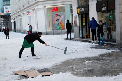 Varias personas retiran este lunes el hielo en la Gran Vía de Madrid.