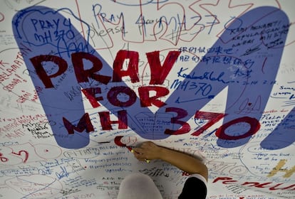 Una empleadda de Malaysia Airlines escribe un mensaje pidiendo oraciones para los pasajeros del vuelo MH371, en el aeropuerto intrernacional de Kuala Lumpur, en Sepang.