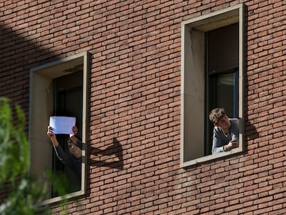 Dos jóvenes miran por la ventana de su habitación en el colegio mayor Penyafort de Barcelona, donde están en cuarentena por un brote de coronavirus.