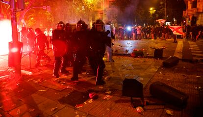 Agentes se agrupan al tiempo que manifestantes lanzan objetos contra ellos el martes.