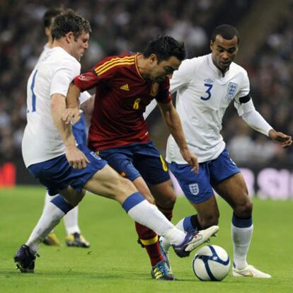 Xavi trata de eludir a Milner y Ashley Cole en el partido del sábado entre Inglaterra y España en Londres.