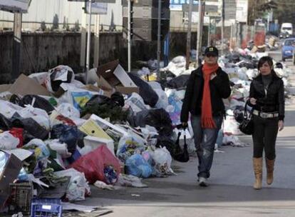 Dos transeúntes pasean rodeadas de basura por una calle de Nápoles, donde los desperdicios se acumulan cada día.