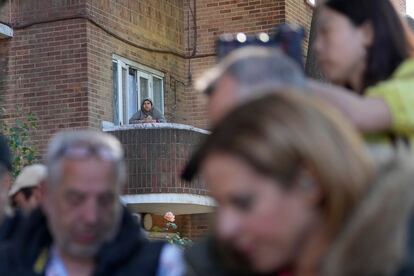 A local resident looks from a balcony at members of the press waiting outside a polling station in London on Thursday. 