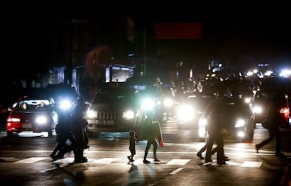 Las luces de los automóviles alumbran el camino de vuelta a casa de un grupo de transeúntes.