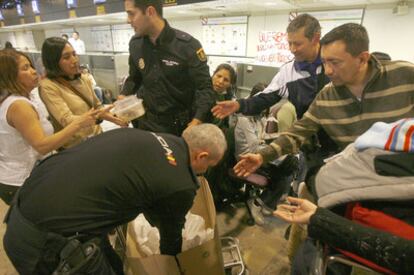 Dos policías nacionales reparten sus cenas de Nochebuena entre los pasajeros de Air Comet en la terminal T-1 de Barajas.