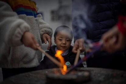 Un niño observa a sus padres encendiendo incienso como ofrenda a sus ancestros en el templo de jade de Buda, en Shanghái, China. El Año Nuevo lunar se celebra el 12 de febrero y marca el principio del Año del Buey.