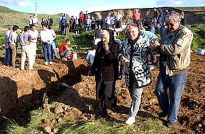 Dos ancianas que tienen enterrados familiares en la fosa comn de Piedrafita de Babia pasan junto a la zanja.