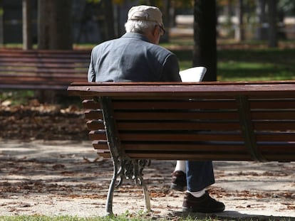 Un hombre lee el periódico en un parque de Madrid.