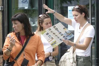 Dos turistas consultan un plano de San Sebastián a las puertas de la Oficina de Turismo.