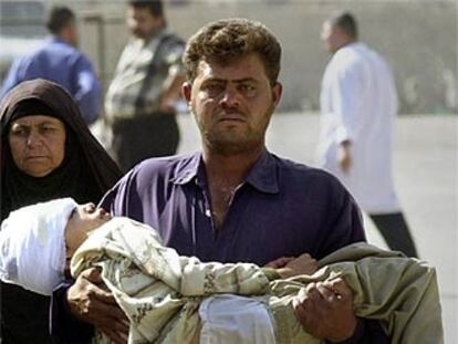 Un hombre lleva en brazos a su sobrino herido, ayer en un hospital de Bagdad.