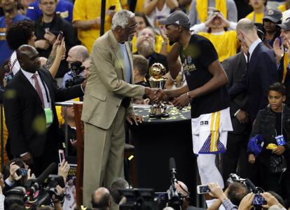 Kevin Durant (d), el jugador de los Warriors, recibe el trofeo del campeonato de manos del exjugador Bill Russell (i), en el Oracle Arena de Oakland, en California.