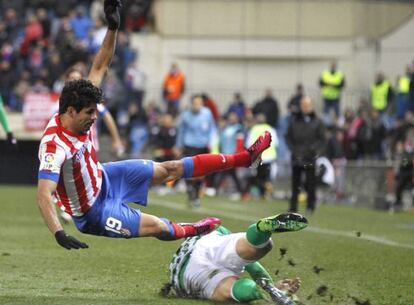 Atl&eacute;tico Madrid&#039;s Diego Costa falls under challenge from a Real Betis player.