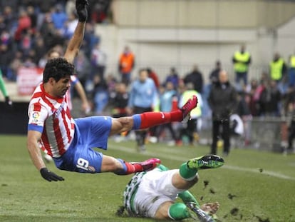 Atl&eacute;tico Madrid&#039;s Diego Costa falls under challenge from a Real Betis player.