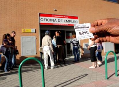 Un hombre enseña un tique con su número de turno delante de la oficina del Inem de la calle de la Virgen del Puig.