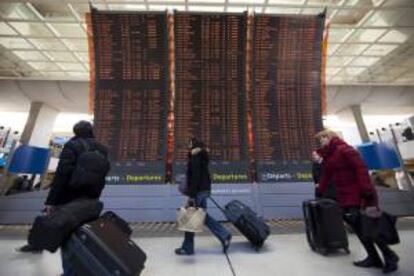 Pasajeros caminando junto a los carteles informativos referentes a las llegadas y salidas de vuelos en la terminal del aeropuerto internacional de Charles-de-Gaulle, durante la huelga de 2012. EFE/Archivo