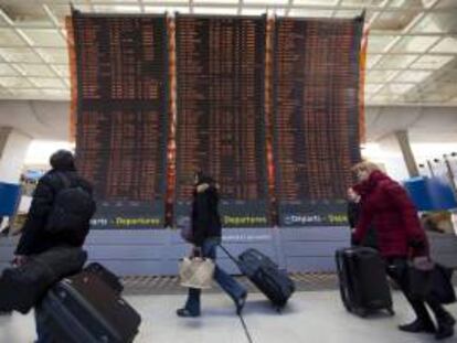 Pasajeros caminando junto a los carteles informativos referentes a las llegadas y salidas de vuelos en la terminal del aeropuerto internacional de Charles-de-Gaulle, durante la huelga de 2012. EFE/Archivo
