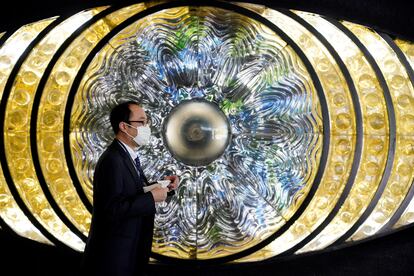 Un hombre protegindo con una mascarilla pasa ante la obra de arte 'Eye of Shinjuku' en la estación de Shinjuku en Tokio, Japón,