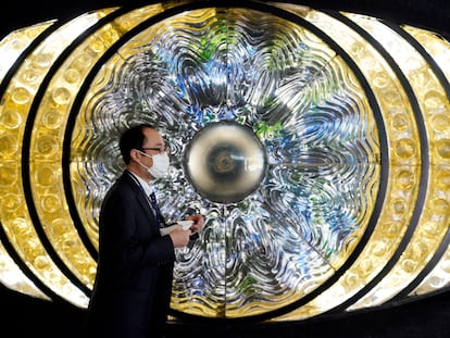 Un hombre protegindo con una mascarilla pasa ante la obra de arte 'Eye of Shinjuku' en la estación de Shinjuku en Tokio, Japón,