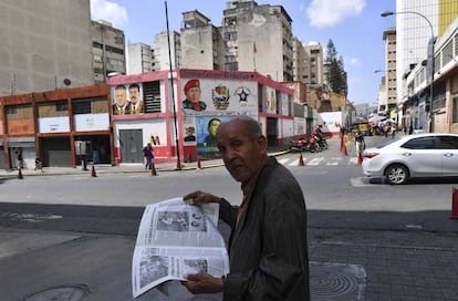 Un hombre lee un periódico, ayer en una calle de Caracas.