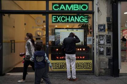 Transeunte olha tela com as cotações das moedas estrangeiras numa casa de câmbio no centro de Buenos Aires.