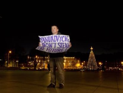 Un hombre lleva una pancarta que reza &quot;&iexcl;Yanukovich: no robes el futuro!&quot; frente al palacio de Vilna donde se celebra la cumbre europea.