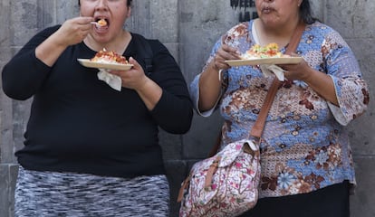 Dos mujeres comen chicharrones preparados en una calle de Ciudad de México.