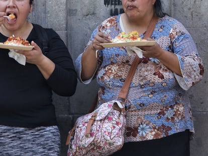 Dos mujeres comen chicharrones preparados en una calle de Ciudad de México.