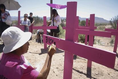 Una madre pinta en una cruz el nombre de una víctima de feminicidio.