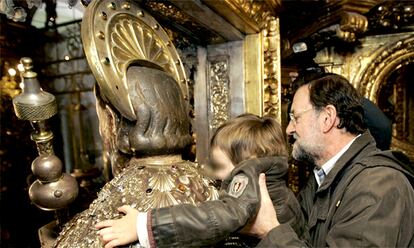 El presidente del PP sostiene en brazos a su hijo mientras éste abraza la imagen del apóstol en la catedral de Santiago.
