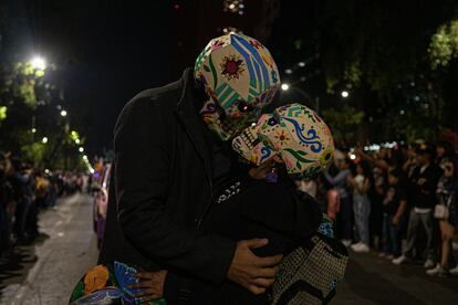 La ciudadanía estuvo invitada a desfilar por las calles del centro, el único requisito era portar un disfraz representativo del Día de Muertos. En la imagen, una pareja con máscaras de calaveras de azúcar se besa durante la Megaprocesión. 