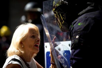 Una mujer conversa con un agente de los Mossos d'Esquadra que ha sido cubierto con pintura de colores lanzada por los manifestantes independentistas que pretendían boicotear una manifestación de la asociación de policías y guardias civiles Jusapol.