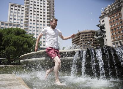 Un turista se refresca en una fuente de Madrid.