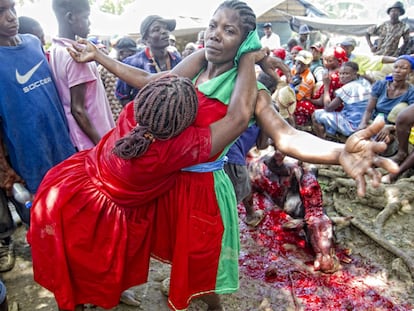 Ritual con sacrificios. El matarife degüella a la vaca y un chorro de sangre salpica al grupo mientras la santera es abrazada por otra mujer.