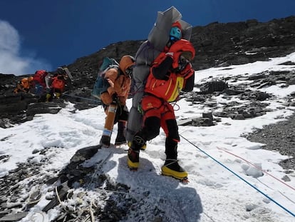 Un sherpa walks transporta a un escalador malasio para rescatarlo en el Monte Everest.