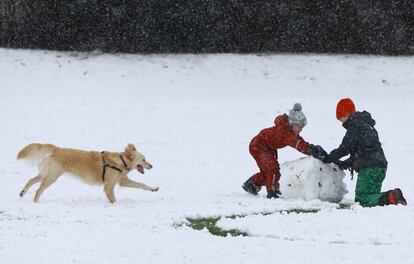 Una familia construye un muñeco de nieve en un parque, al norte de Londres (Inglaterra).