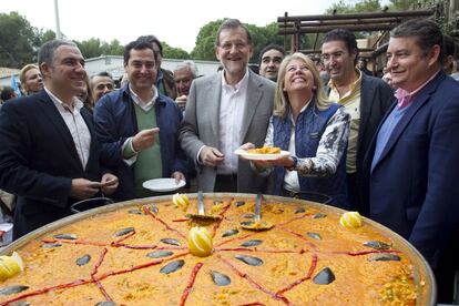 El presidente del Gobierno, Mariano Rajoy (c), acompañado del presidente regional del Partido Popular, Juanma Moreno (2i), del presidente provincial, Elías Bendodo (i), de la exalcaldesa de Marbella, Ángeles Muñoz (2d) y del delegado del Gobierno en Andalucía, Antonio Sanz (d), sirven una paella en un almuerzo-mitin en el Albergue Fuerte de Nagüeles de Marbella.